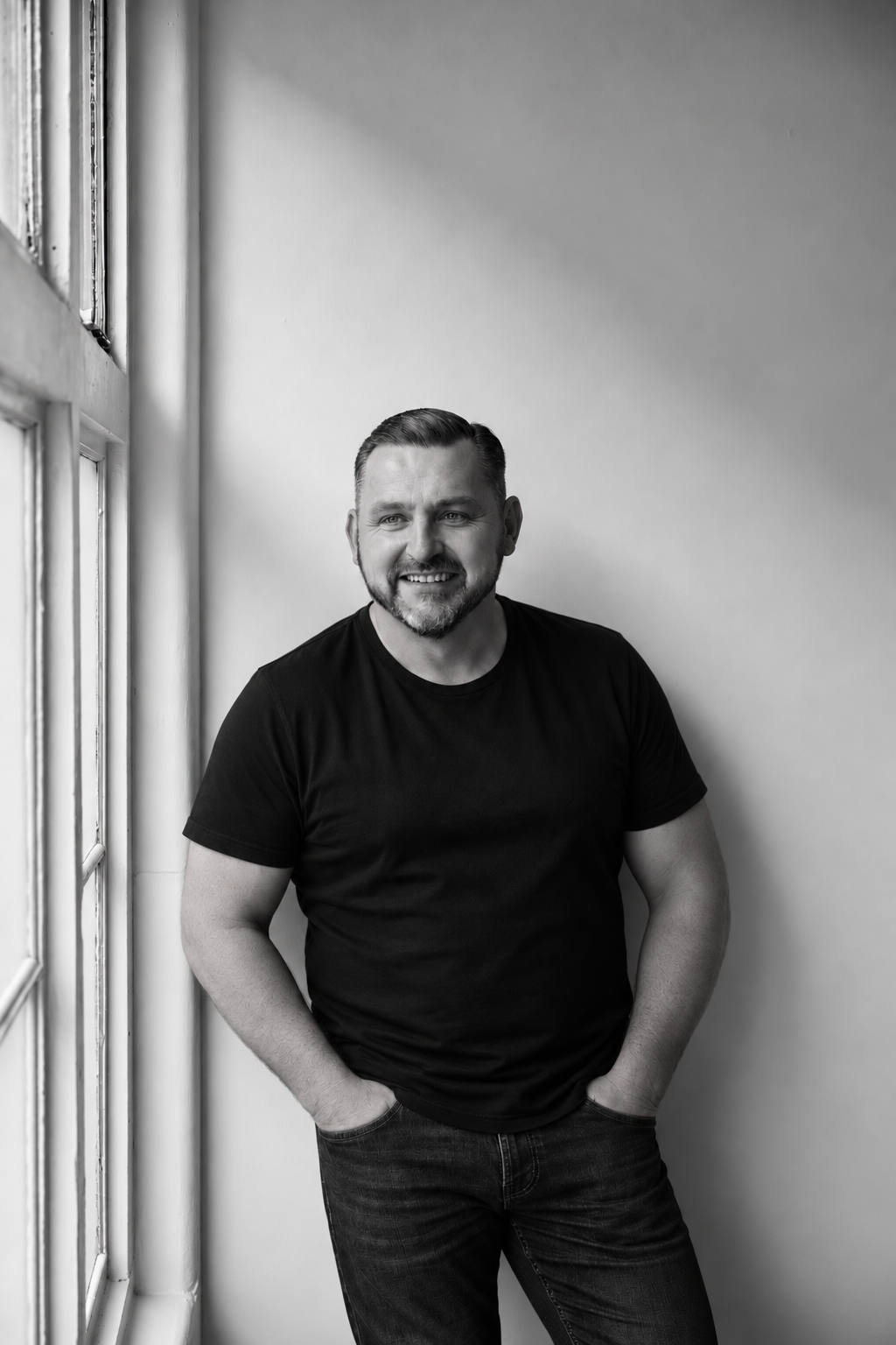 Black-and-white portrait of IAMBROON standing by a window